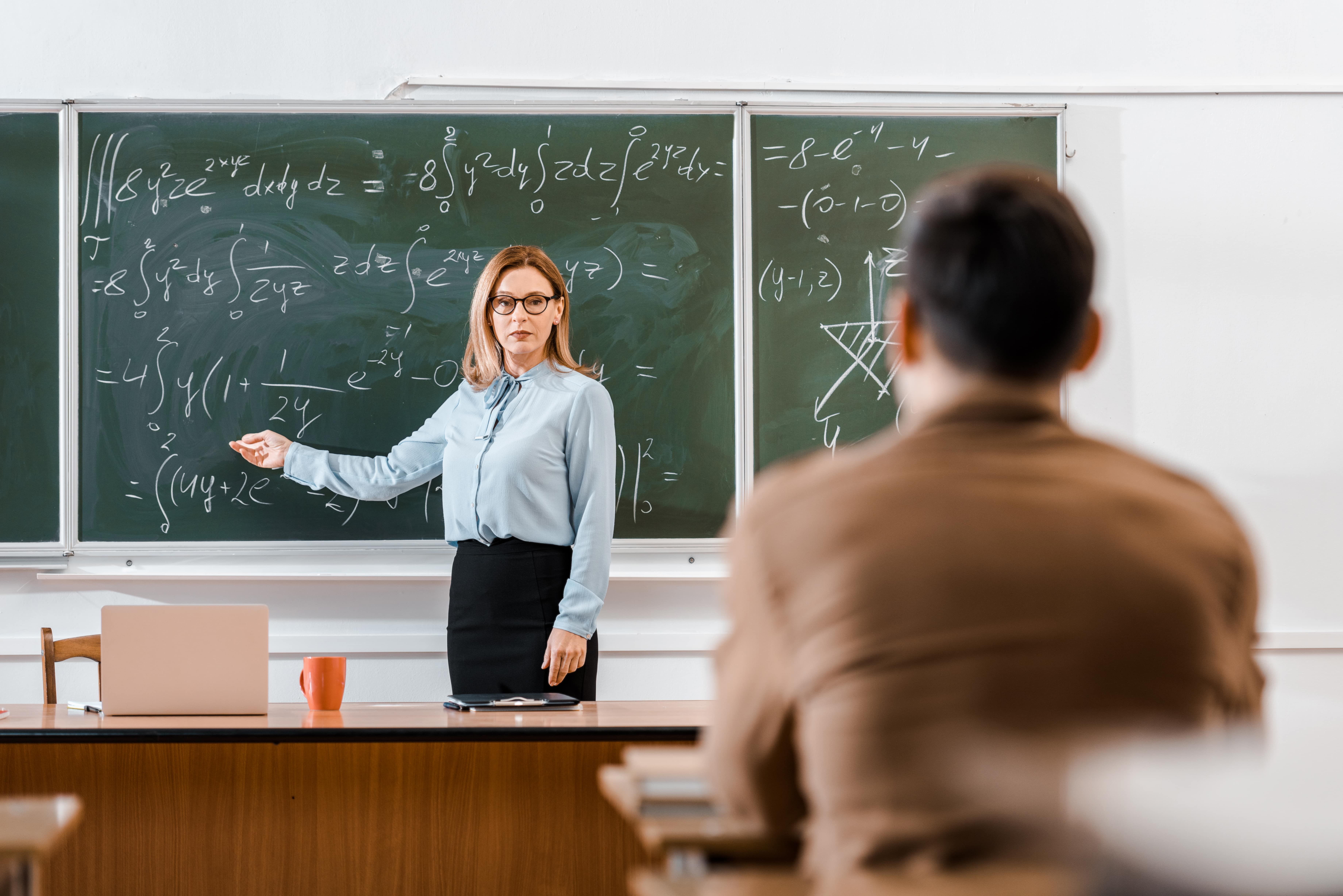 A teacher showing math on a black board
