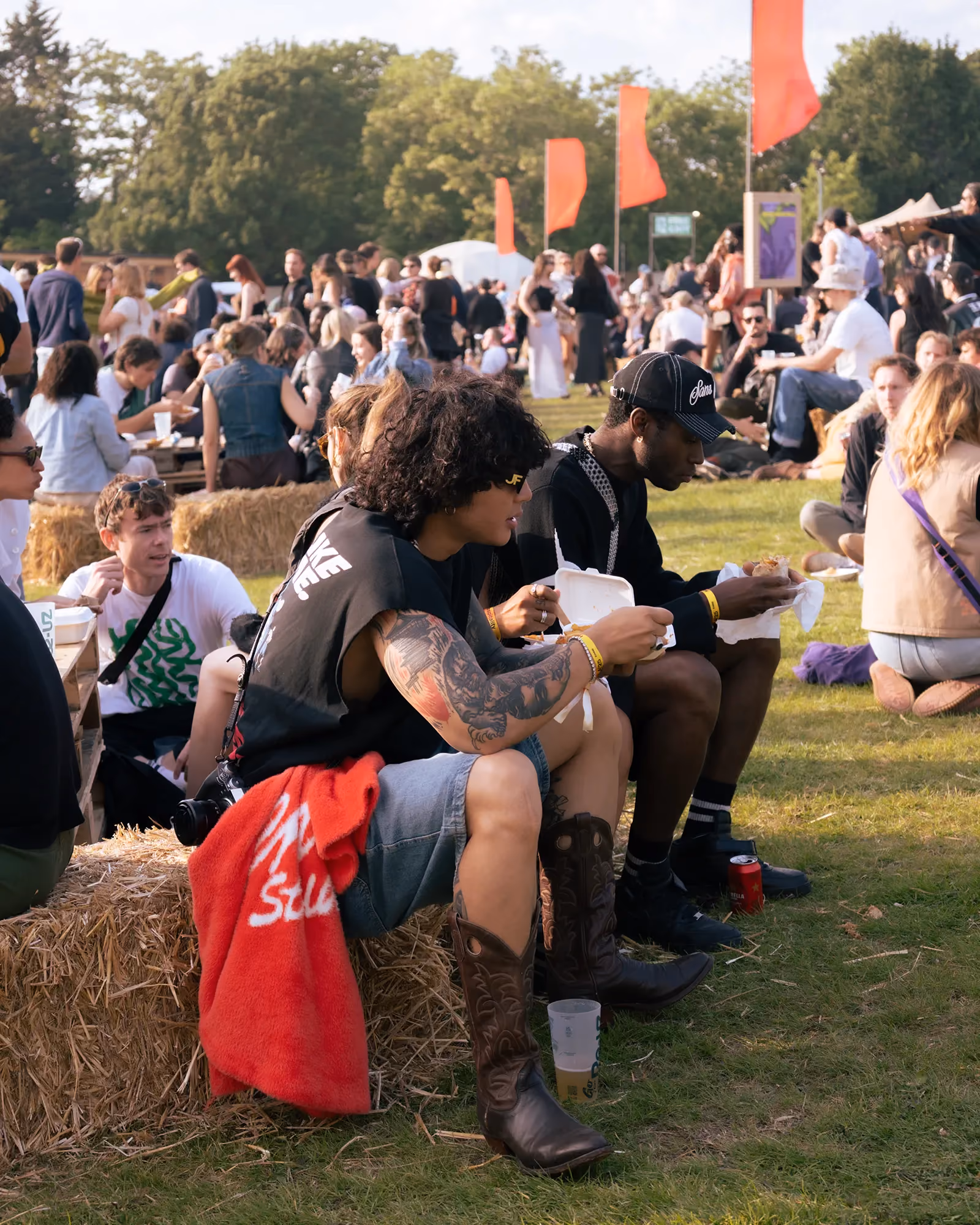 Attendees of Gala festival sit on a hay bale eating food