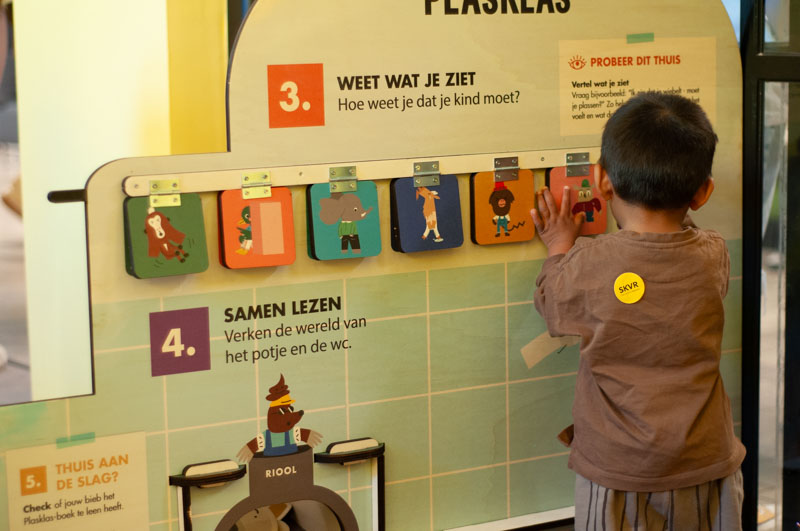Peuter zit op een potje en houdt het boek “Ga je mee naar de wc?” voor zich. Spelenderwijs leren zindelijk worden. Klaar? Go Potty!