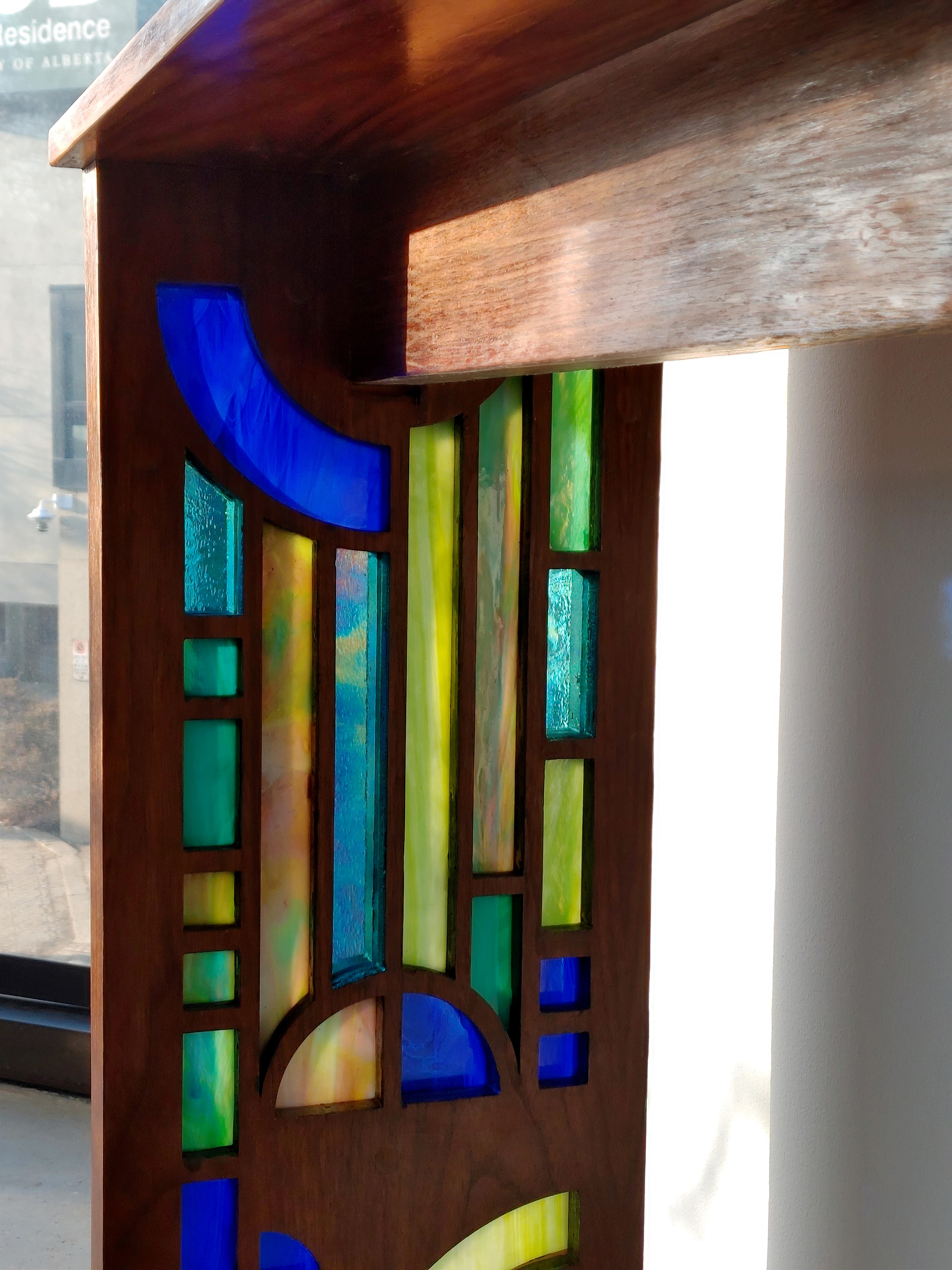 Closer photo of the stained glass detail. The stained glass pieces form a geometric, waterfall style pattern with strong vertical lines and elegant semicircles and arches.