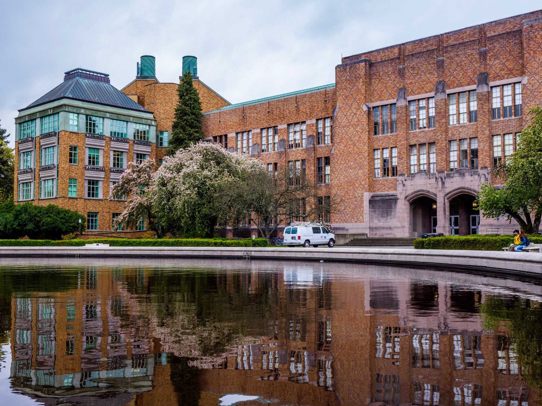Brick school buildings with spring blossoms reflected in a still pool