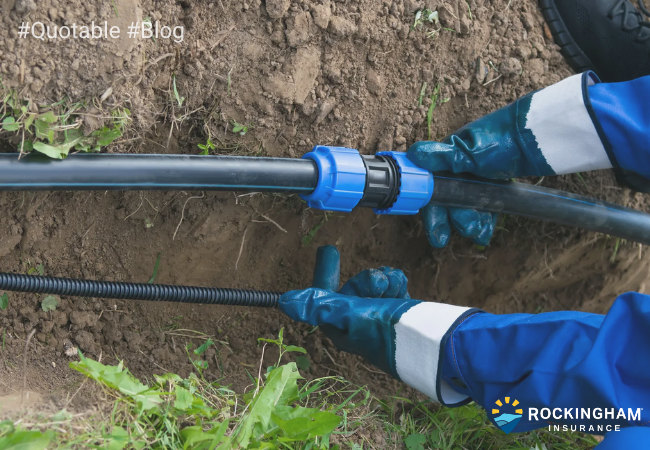 Worker repairing an underground utility service line connection in a residential yard.
