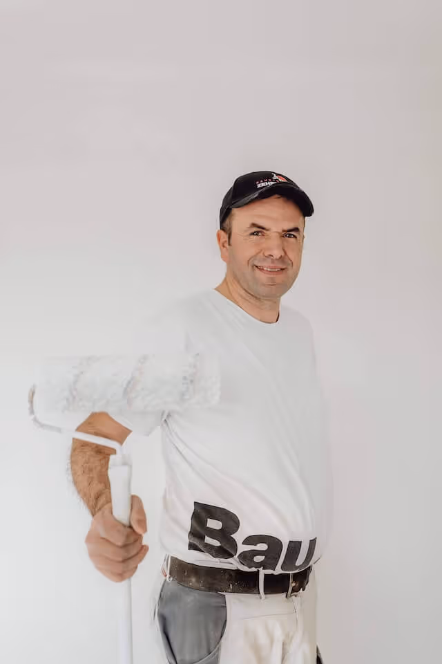 SaniBau Mitarbeiter im weißen T-Shirt mit Farbrolle.