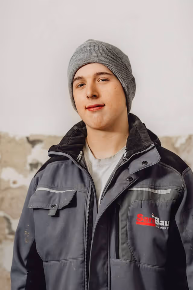 SaniBau Mitarbeiter mit grauer Mütze und Arbeitskleidung.