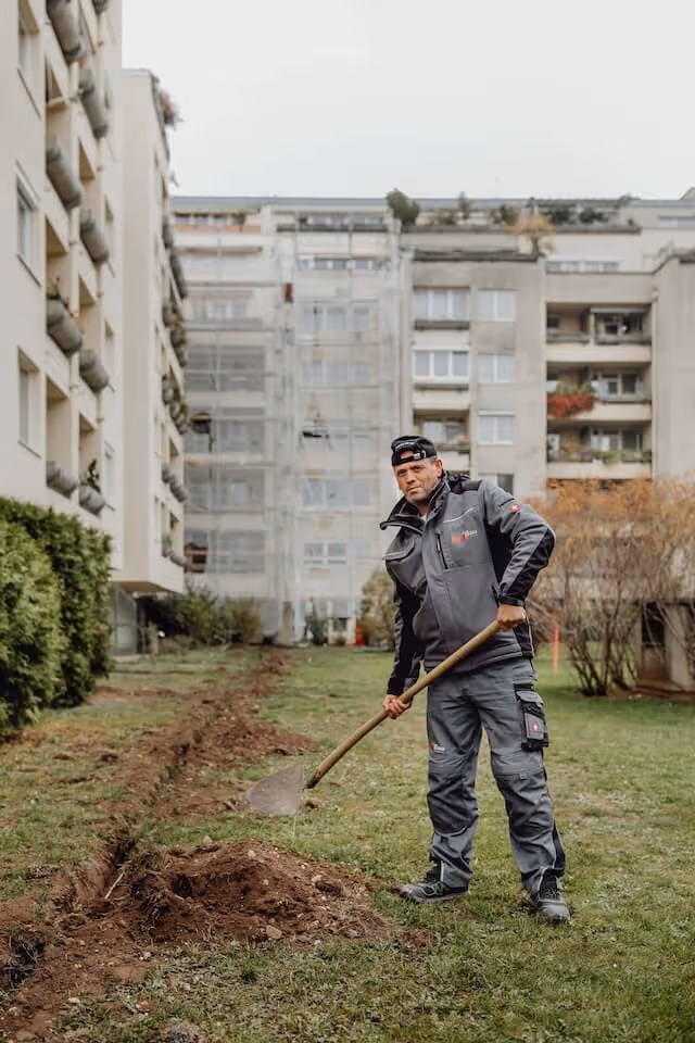 SaniBau Mitarbeiter bei Vermessungsarbeiten im Freien.
