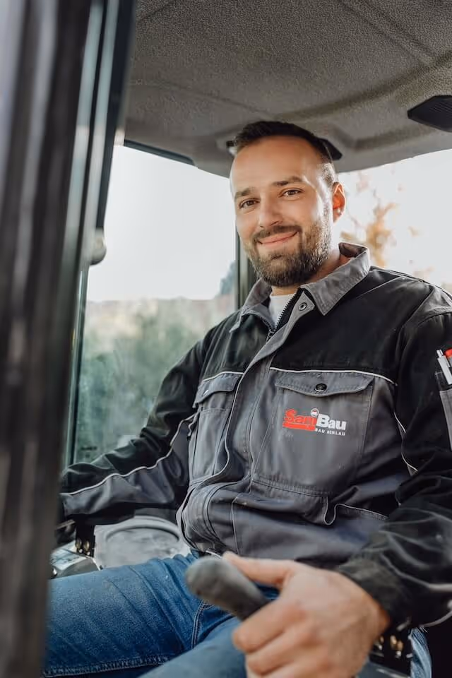 SaniBau Mitarbeiter im Baggerfahrzeug.