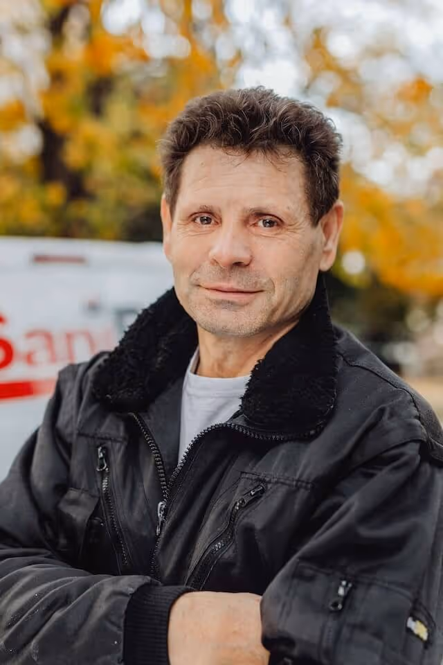 Porträt eines SaniBau Mitarbeiters in schwarzer Jacke.