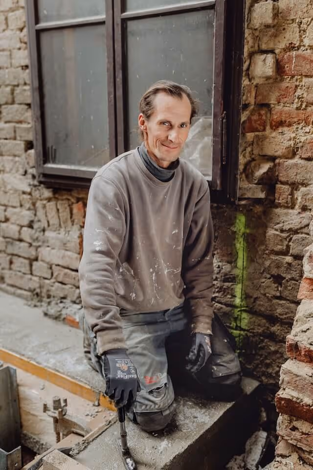 Handwerker mit Bauhelm und Werkzeug im Innenbereich.