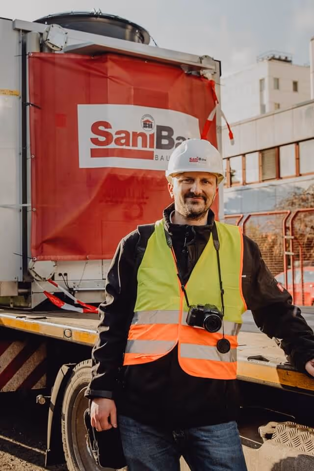 Bauleiter in Warnweste vor SaniBau Container.