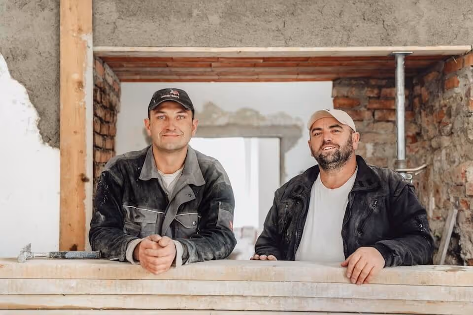 Zwei Handwerker bei Sanierungsarbeiten im Innenraum.