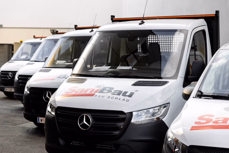 SaniBau Firmenfahrzeuge vor Baustelle in Wien.