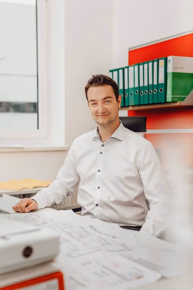 SaniBau Mitarbeiter bei der Bauplanung am Schreibtisch.
