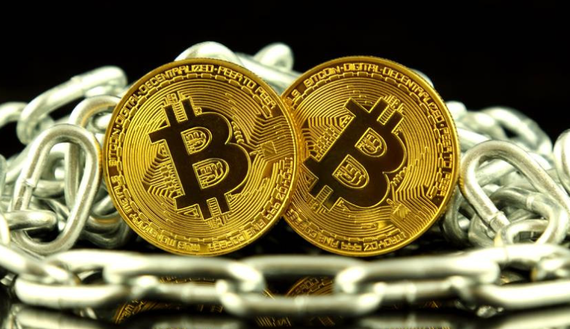 Golden Bitcoin coins with blockchain security concept represented by metal chain links on black background