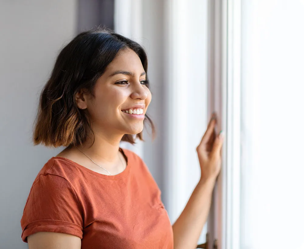 Woman standing and looking out of a window.