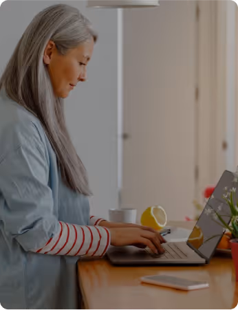 Mature woman working on laptop at home with lemons and coffee nearby