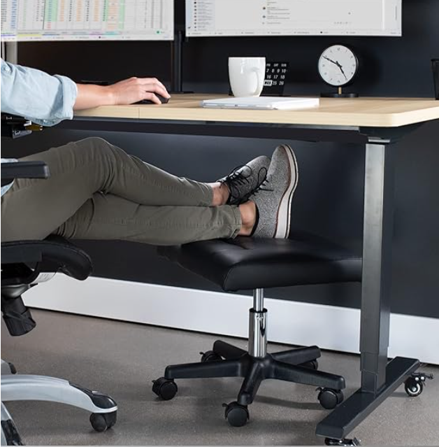 Person resting feet on chair at desk with computer and coffee mug
