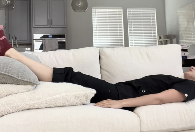 Person wearing black lying exhausted on white couch in bright kitchen