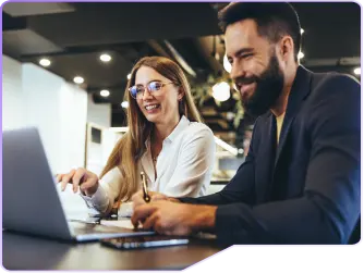 Foto com um homem e uma mulher descontraídos, olhando para o computador analisando os seus bons resultados.