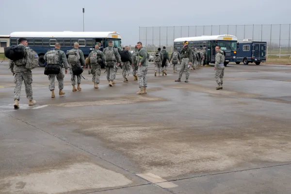 Soldiers move out with gear on the flightline during a deployment