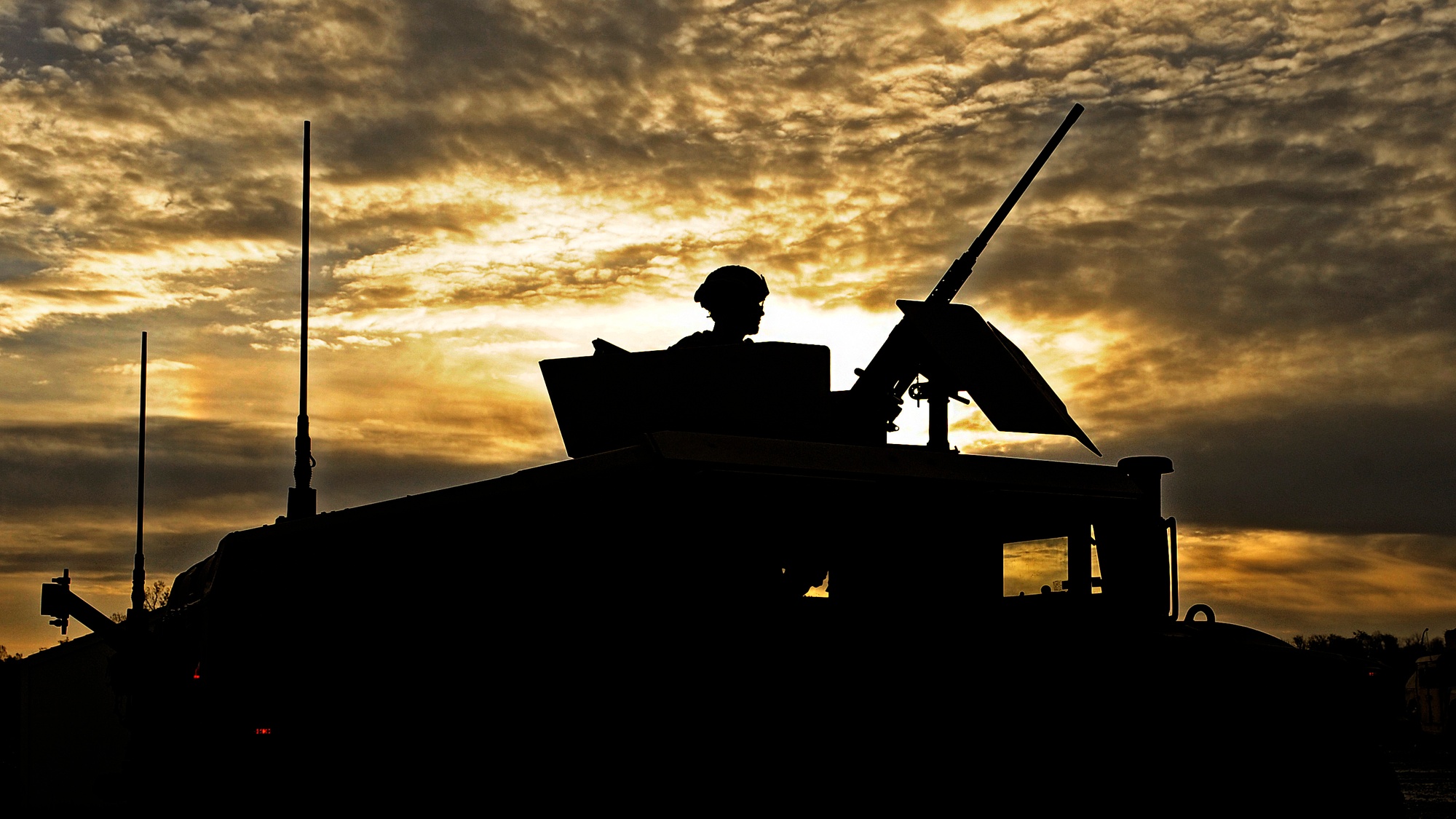 A service member mans a machine gun during a mounted combat patrol on deployment