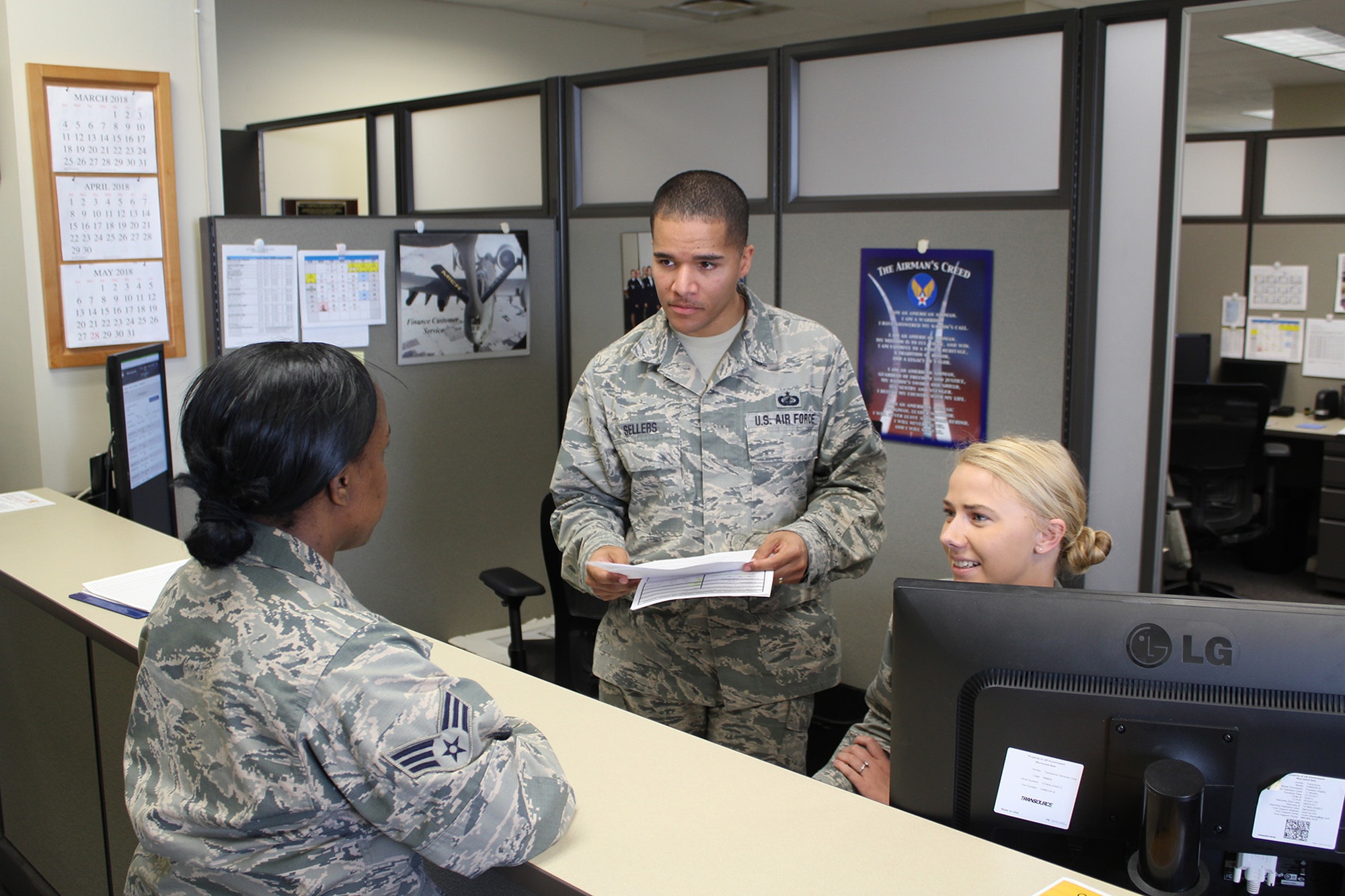 Service members assist a customer at a military finance customer service counter