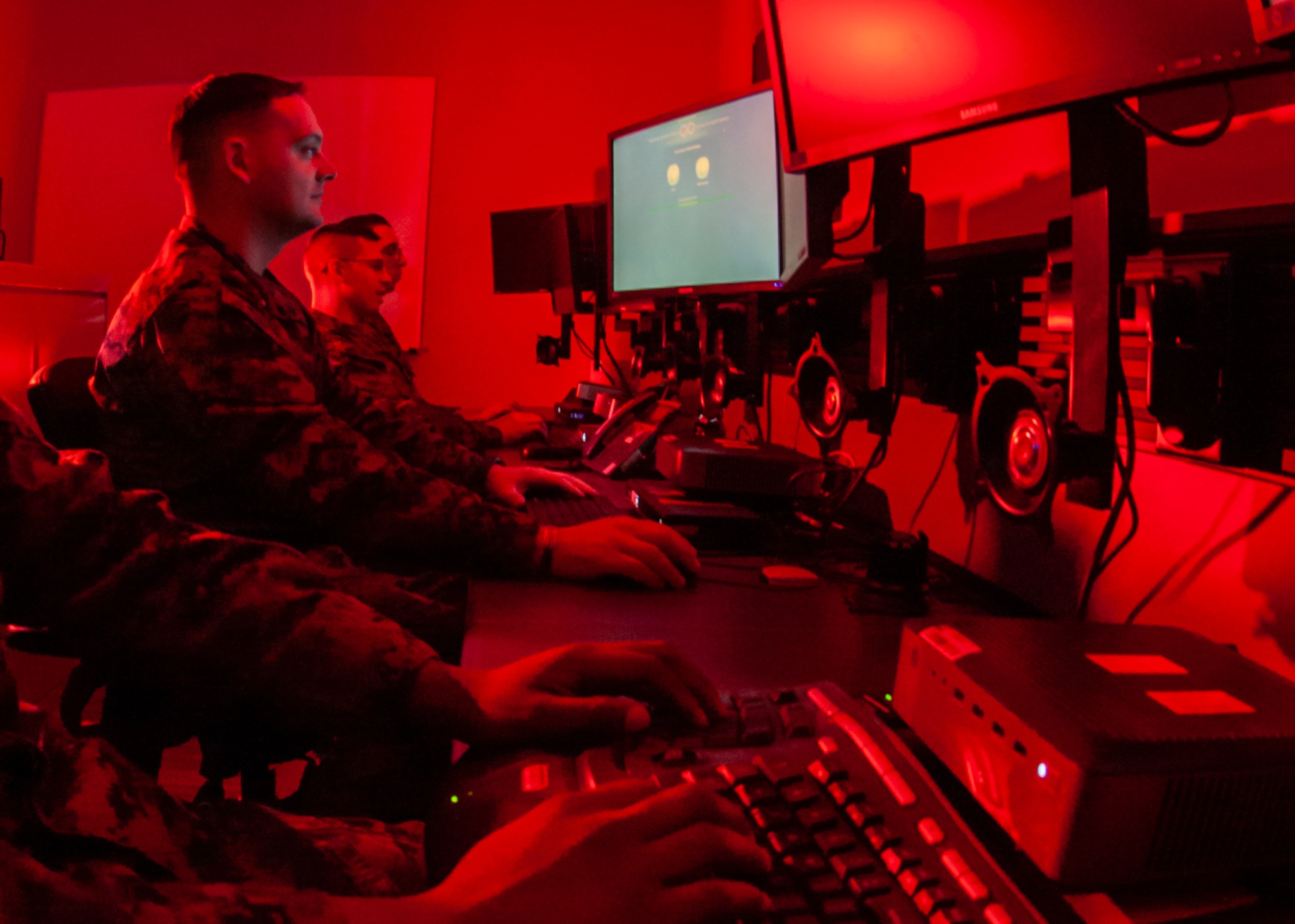 A service member works at a computer keyboard in a cyber operations setting