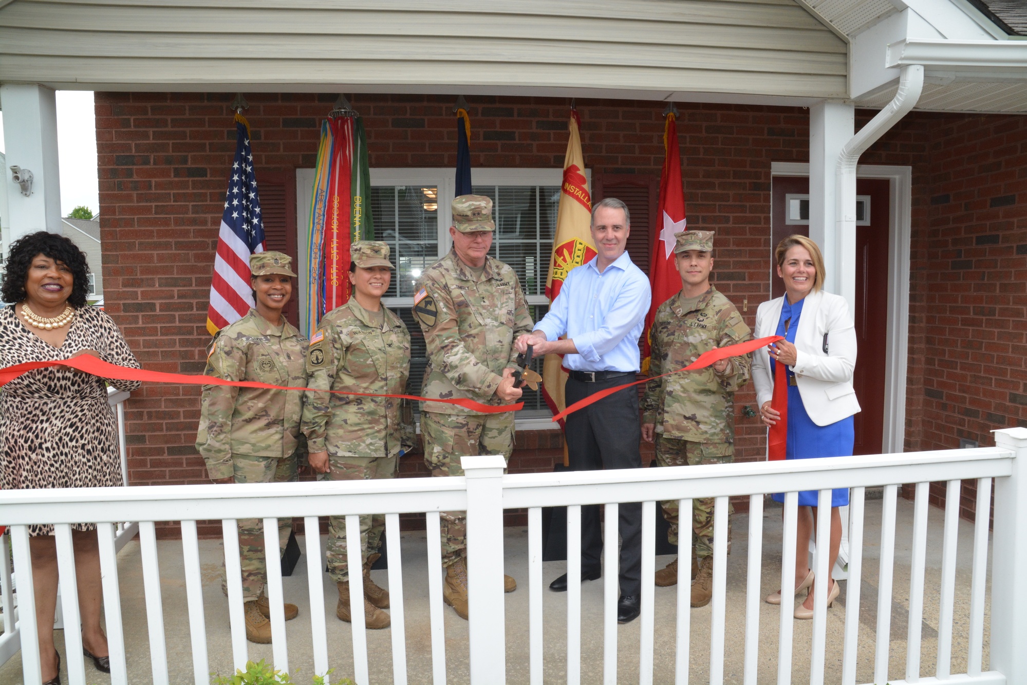 Leaders cut a ribbon to open a newly renovated home with an updated living area and kitchen.