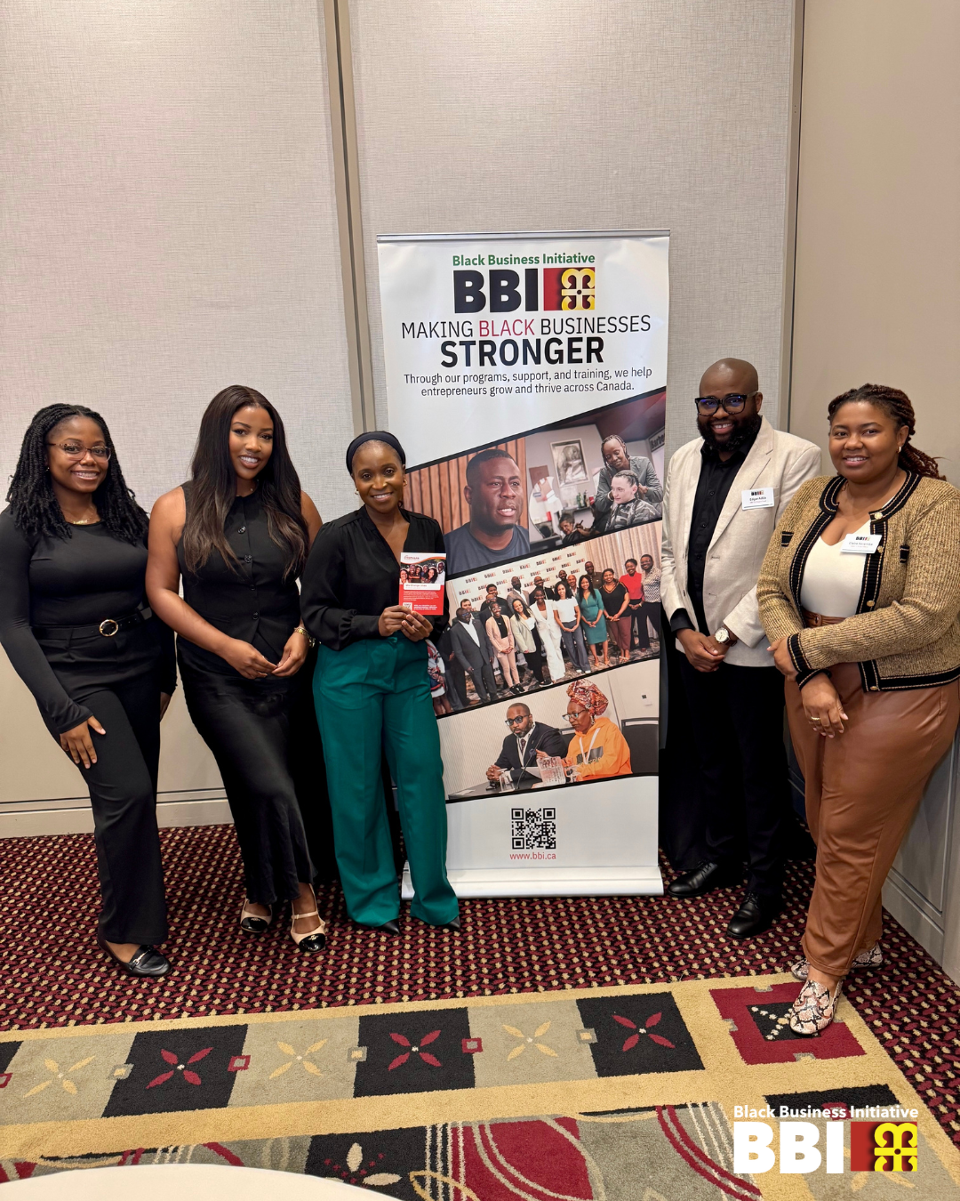 Five individuals posing beside a BBI Banner at an information session in Toronto