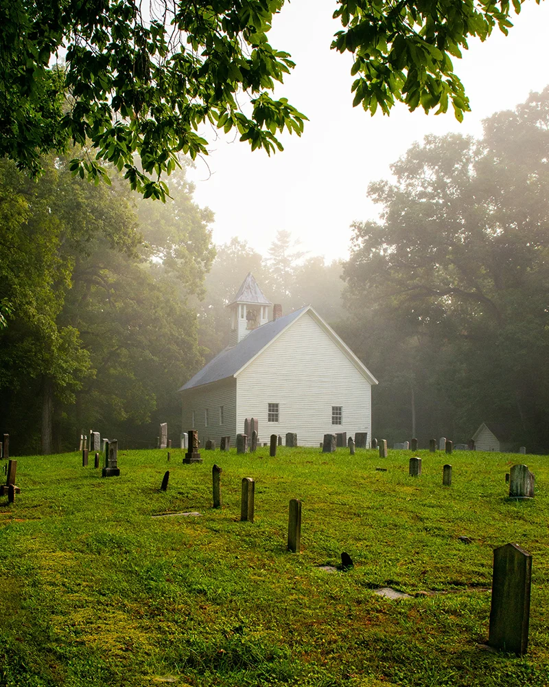 church in grassy clearing with tombstones around it