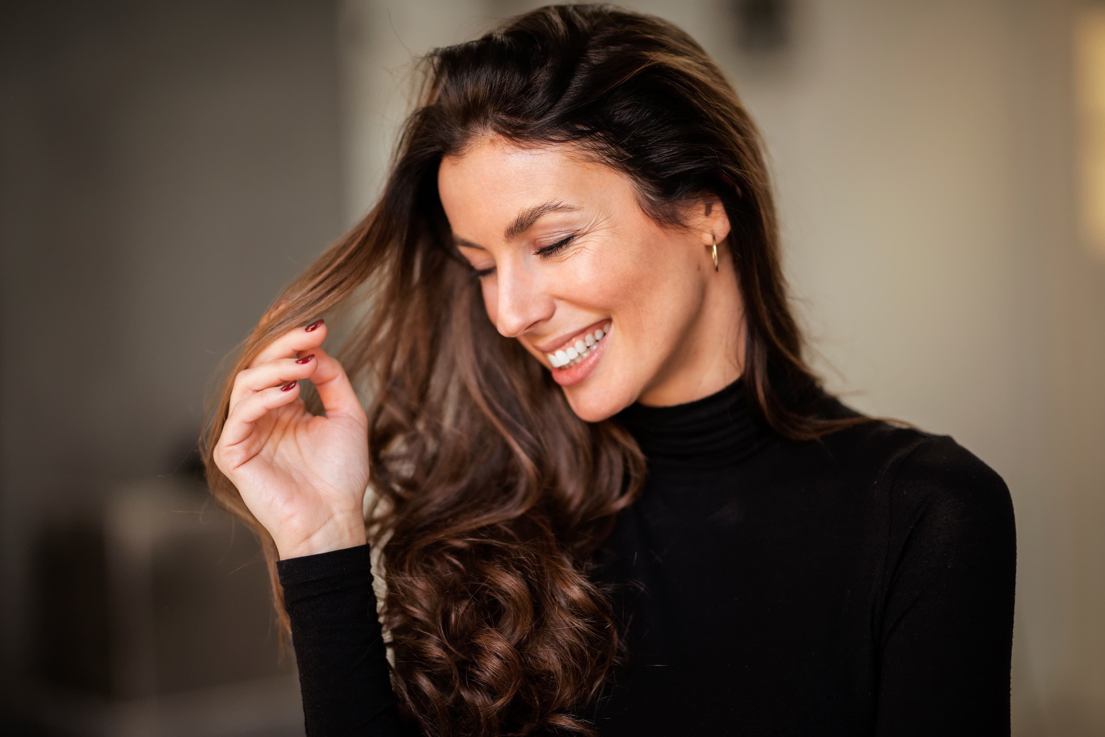A woman with long brown hair is smiling.