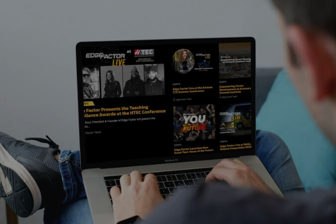 Person using a laptop displaying the Edge Factor Live website with conference and event announcements.