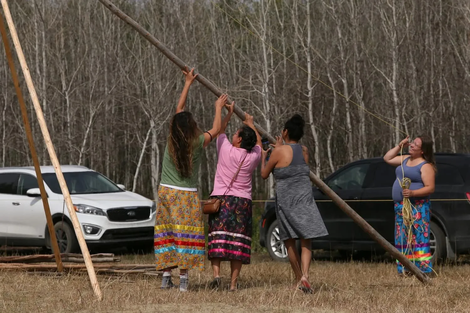 native women building a teepee for the community