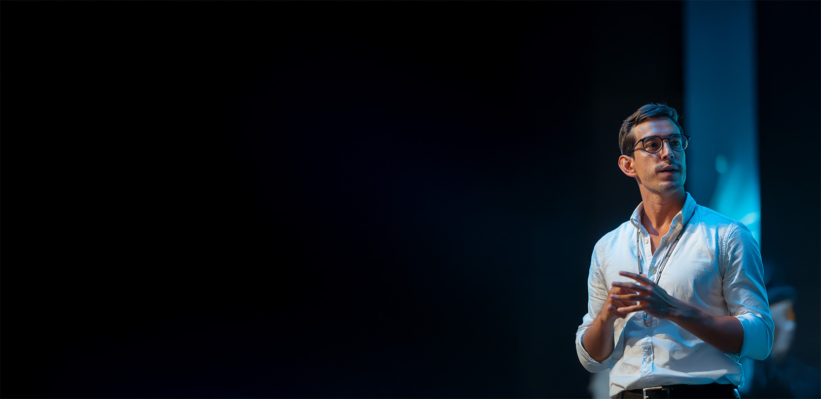 Dark background with a guy doing a conference