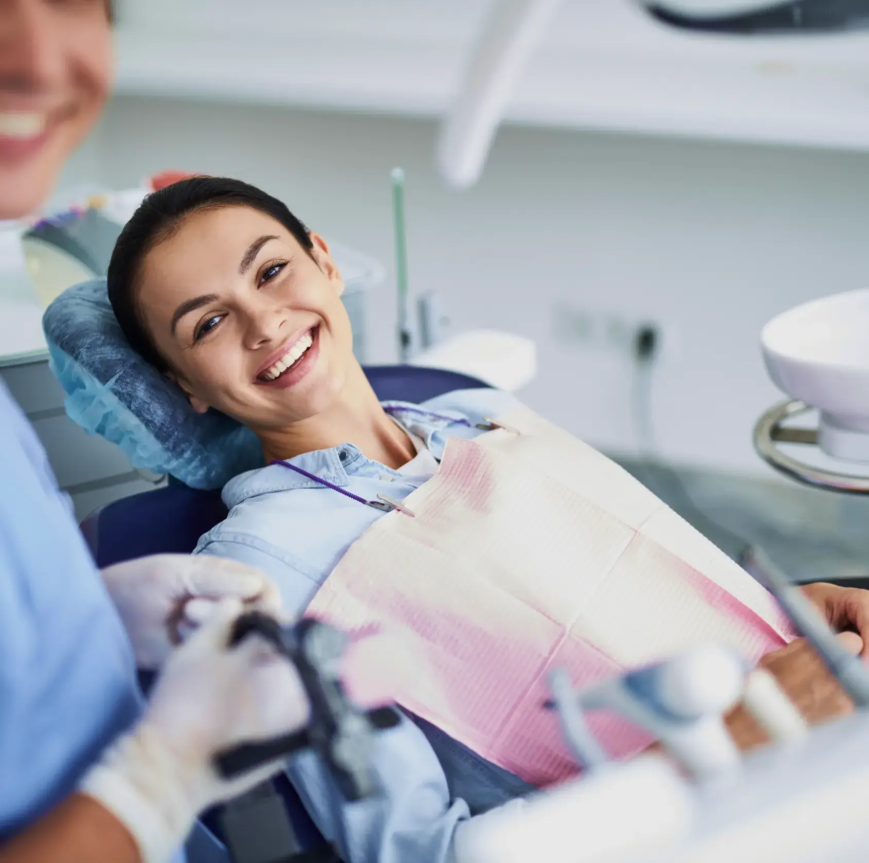 Dental professional adjusts equipment while treating a patient in a dental clinic.