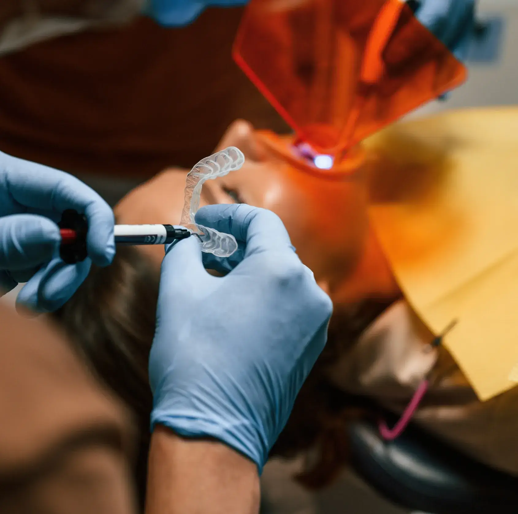 A woman receives a dental X-ray while a dental assistant monitors the procedure.