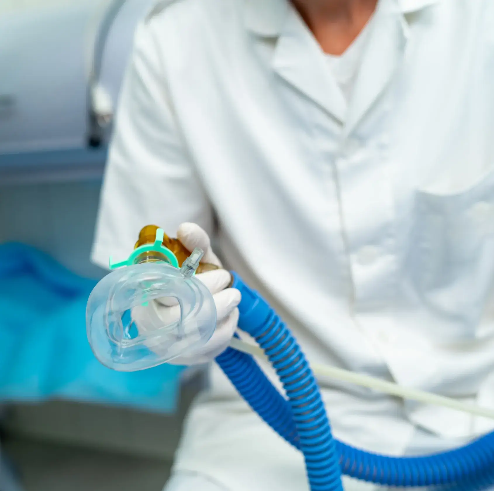 A healthcare worker holds a medical mask with attached hoses.