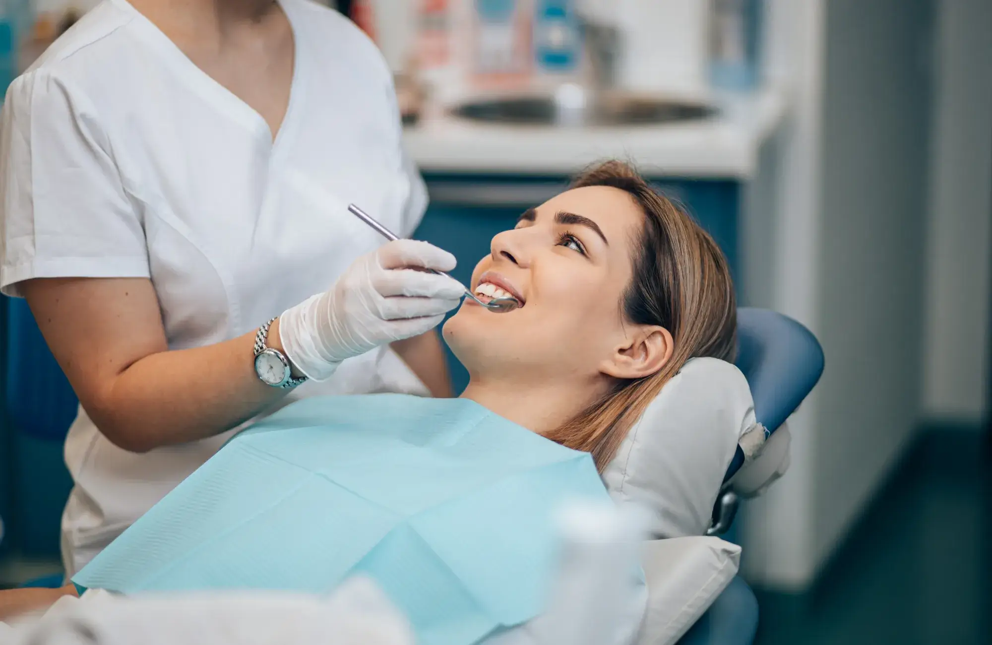 Two dental professionals in protective gear examine dental X-rays on a computer screen.