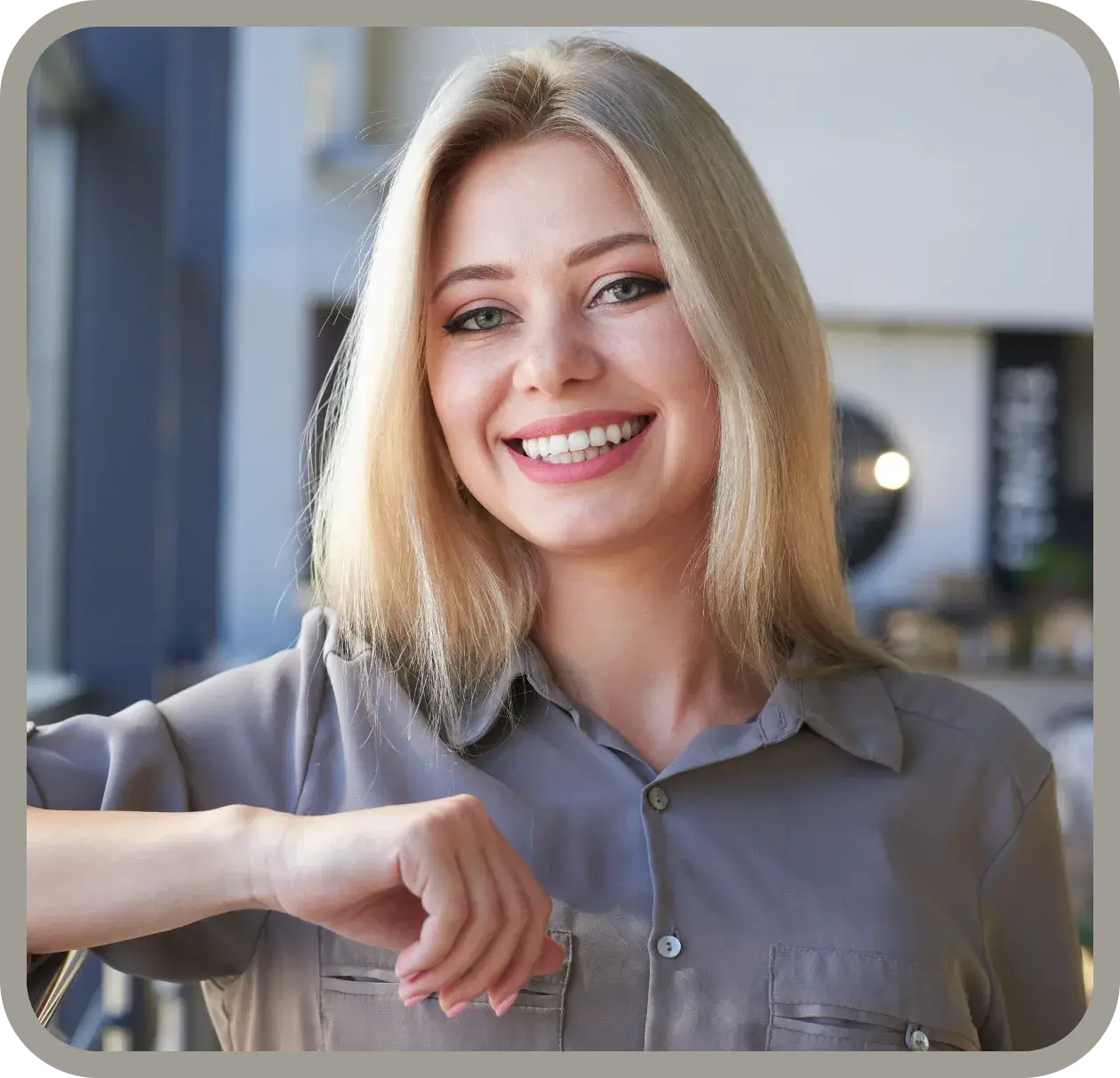 Woman smiling and holding a clear dental aligner while taking a selfie.