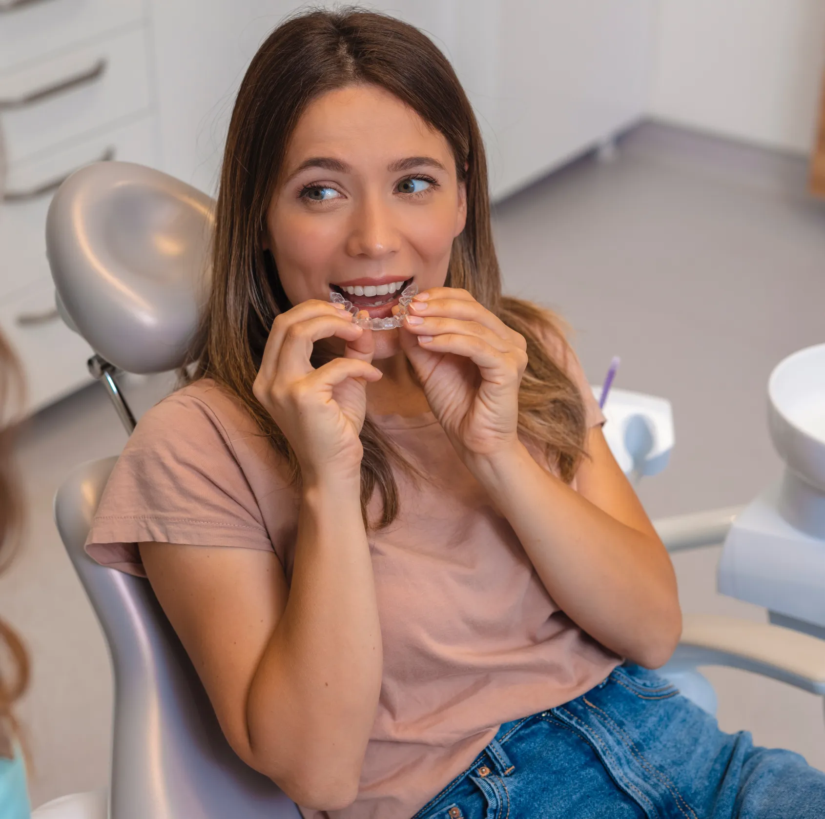 Person holding dental models with braces, one pink and one yellow, demonstrating orthodontic treatments.