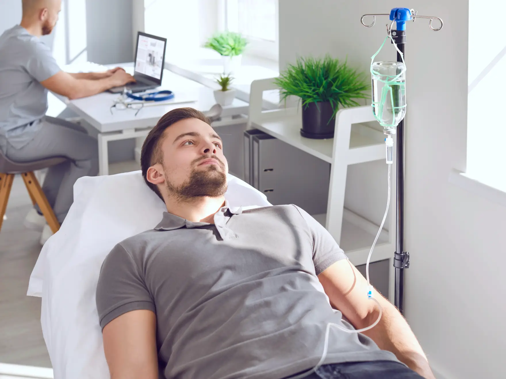 A man is lying on a hospital bed receiving an IV drip.