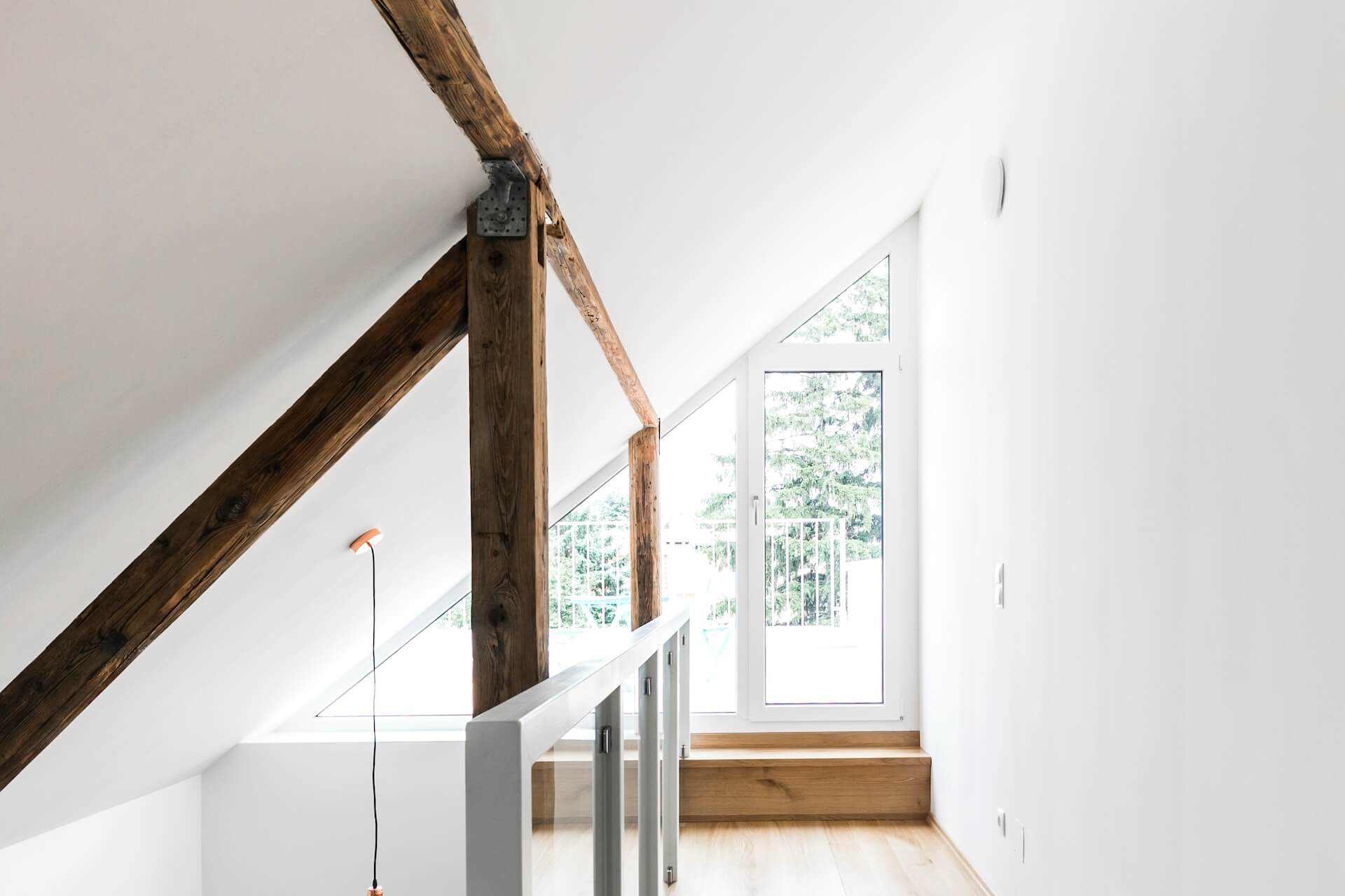 Obergeschoss mit freigelegten Holzbalken und Dachfenster nach Sanierung