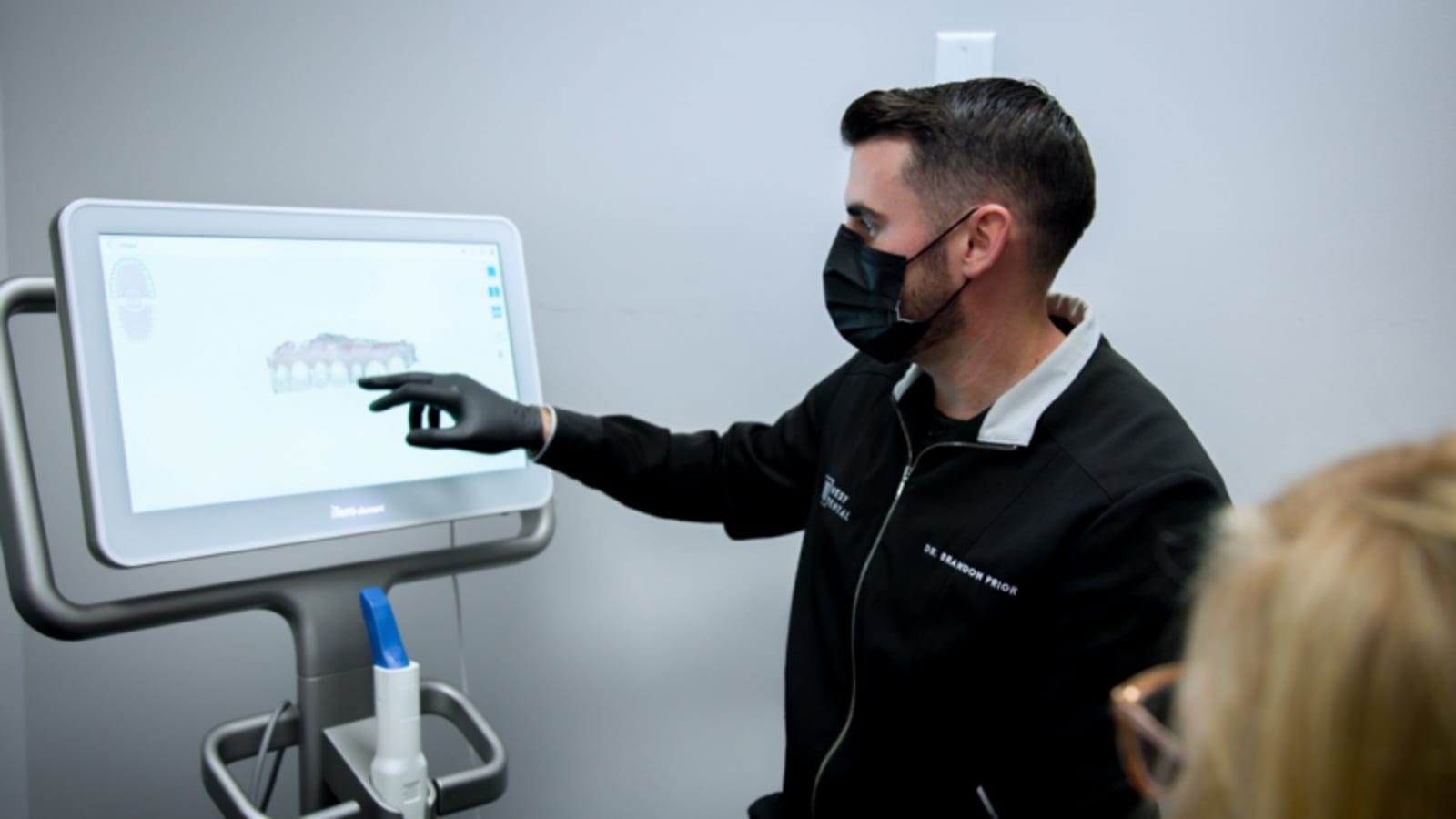 Dentist pointing to digital dental imaging on monitor during patient consultation