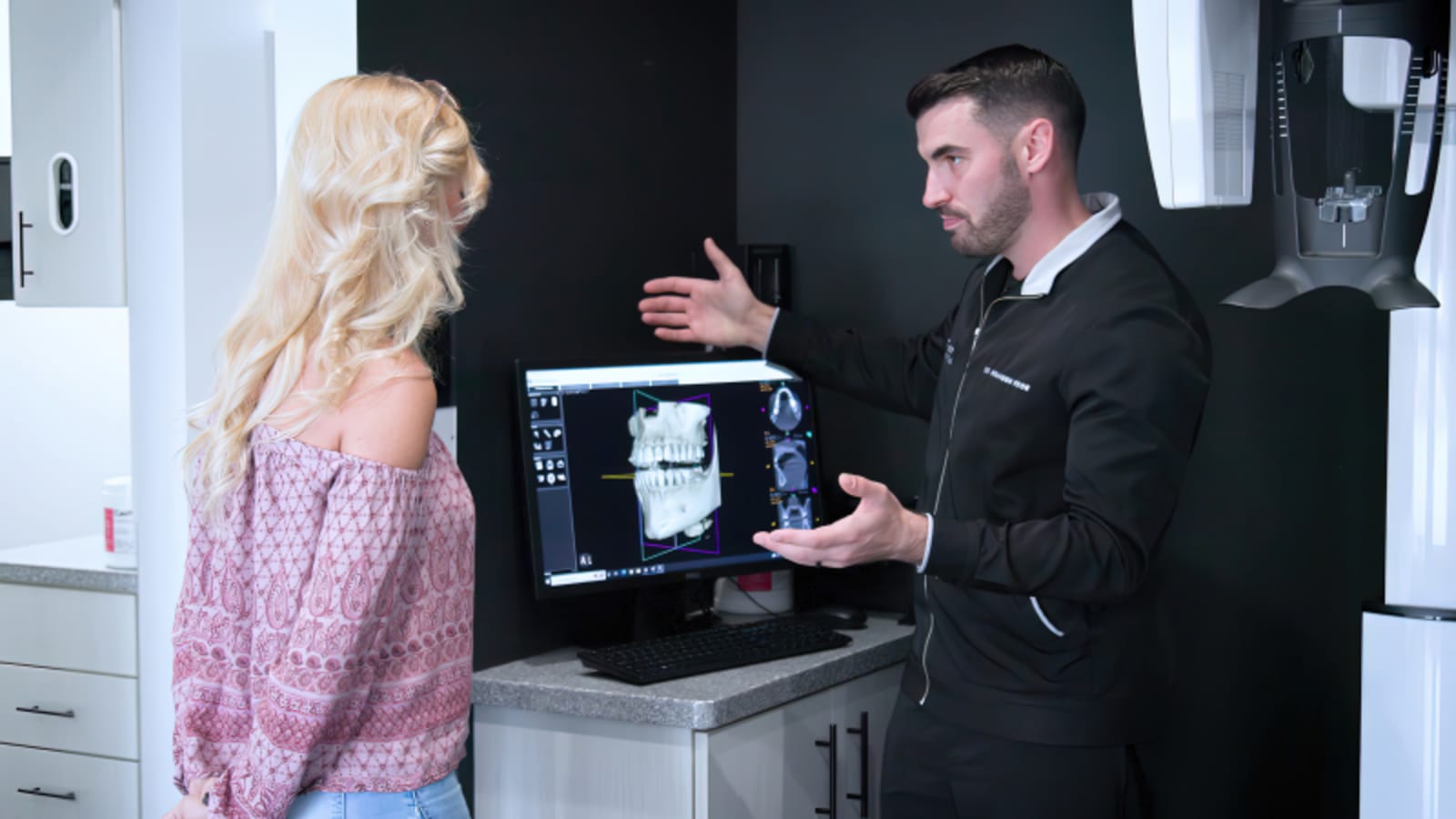 Dentist discussing treatment options with female patient at 100 West Dental office.