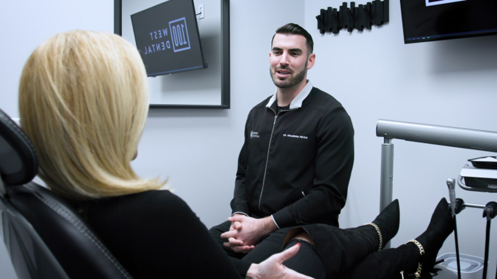 Male dentist consulting with female patient in modern dental office