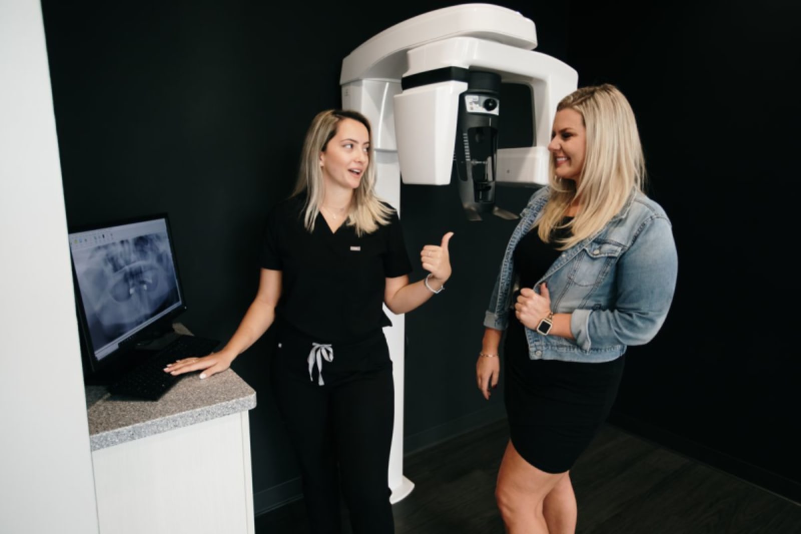 Two dental professionals examining digital smile design on a computer screen during a veneer consultation.