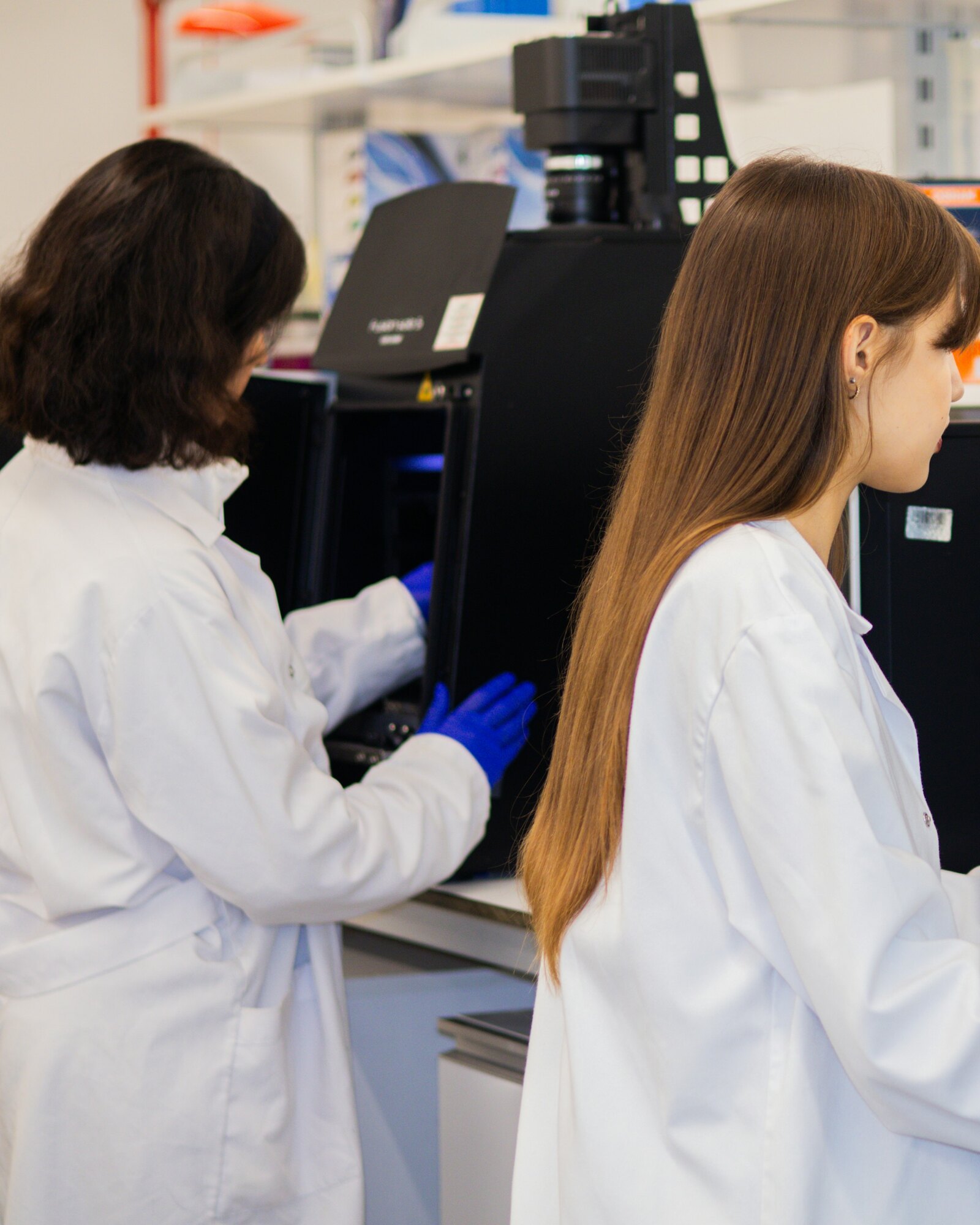 Two laboratory scientists at work in a bright analysis room