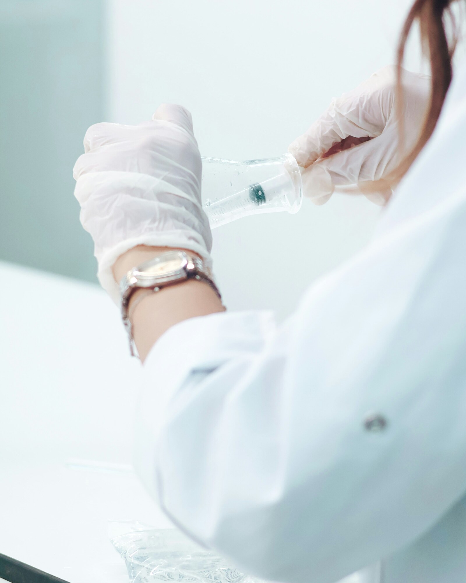 A gloved hand steadying a sample vessel in a bright clinic laboratory