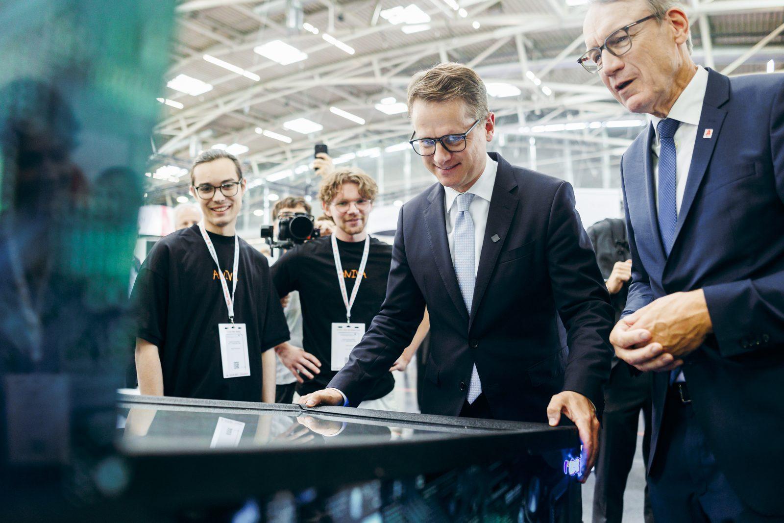 Bundesgesundheitsminister Dr. Carsten Linnemann spielt am Flipper-Tisch auf dem Aniva-Stand der expopharm 2026 in München, neben ihm das Aniva-Team. Foto: BMG/Xander Heinl