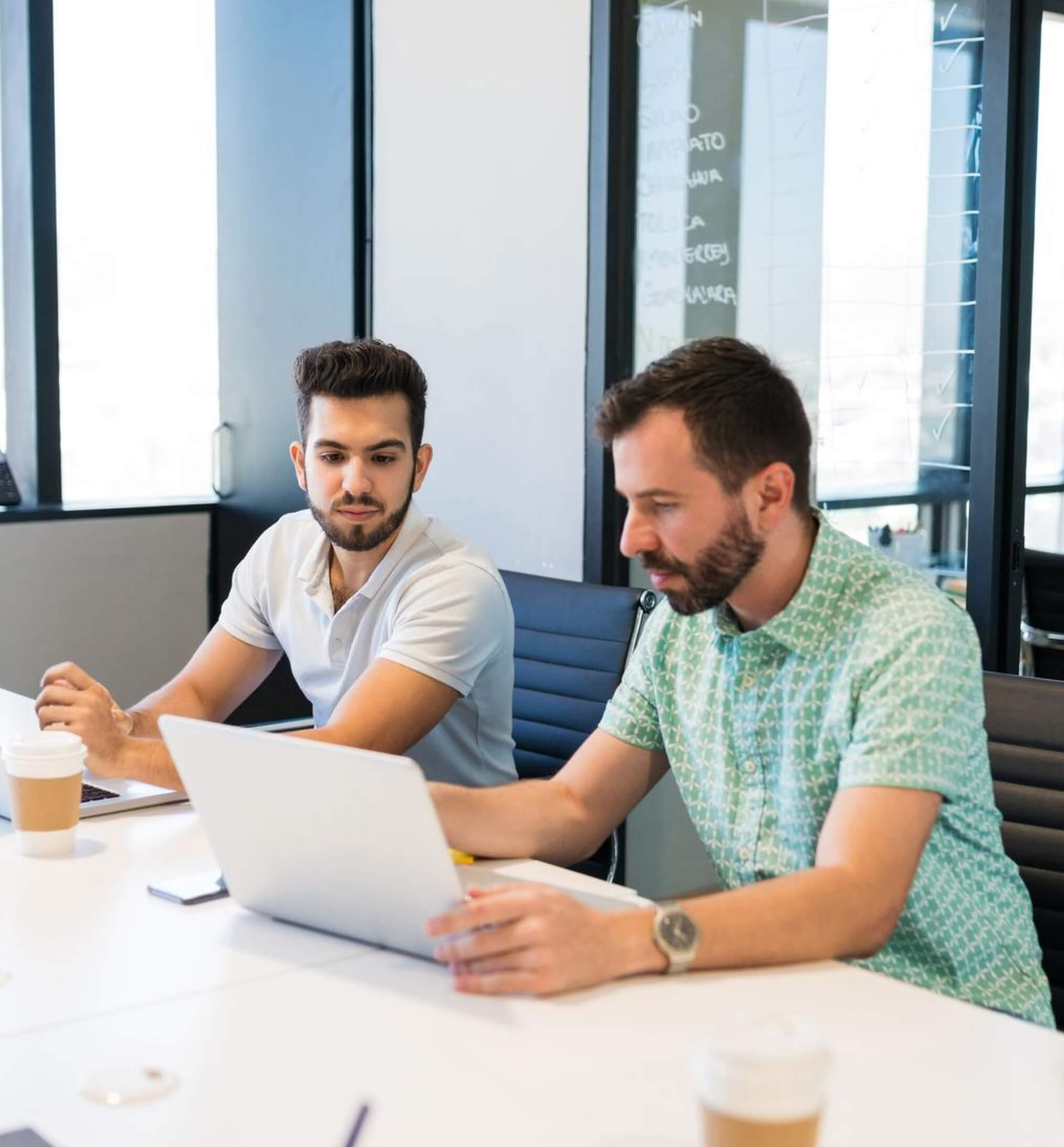Two men sitting at a table with a laptop.