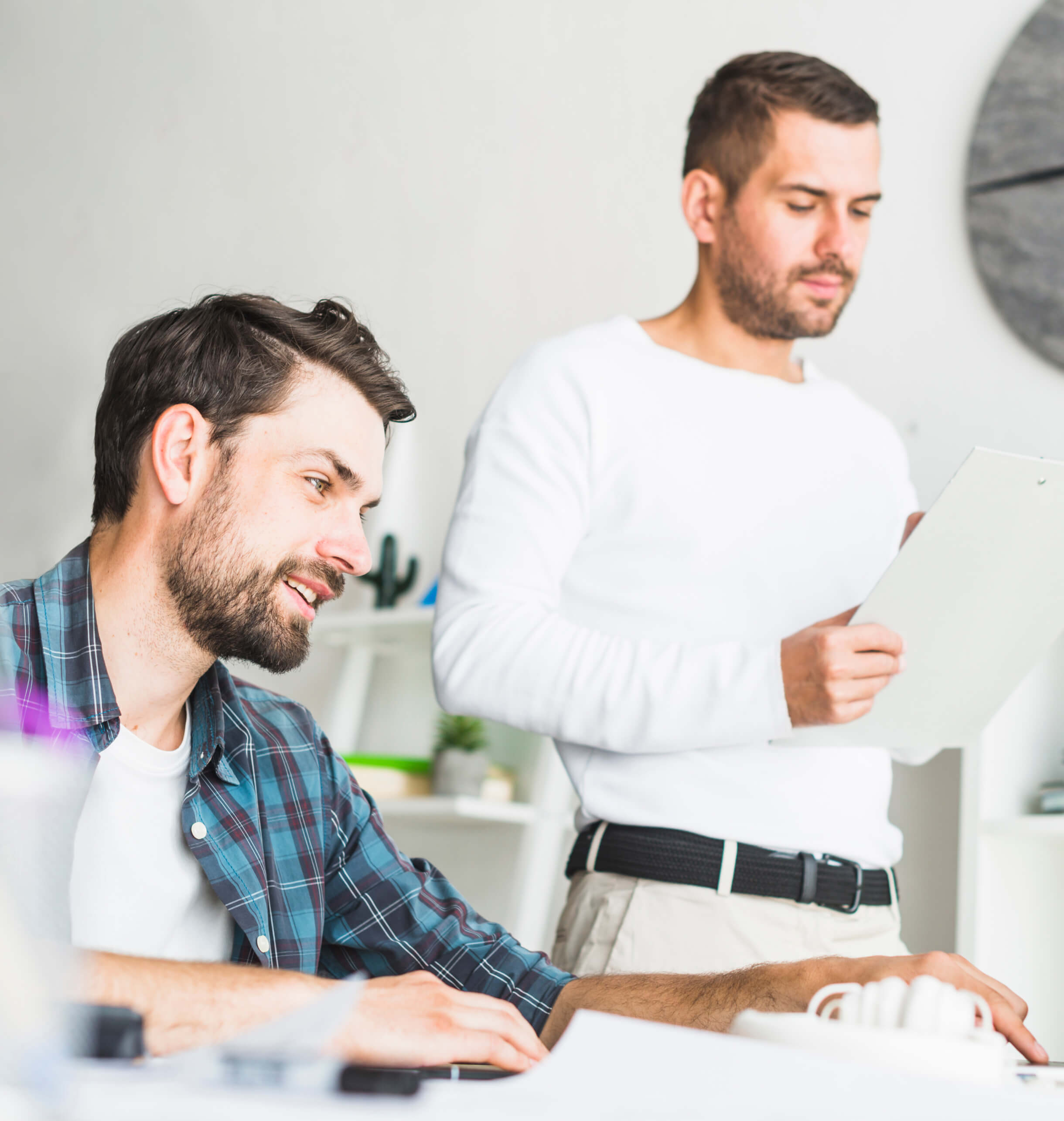 Two men sitting at a table looking at a piece of paper.